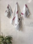 Three towels, one bath and two hand towels, all white with pink palm tree designs