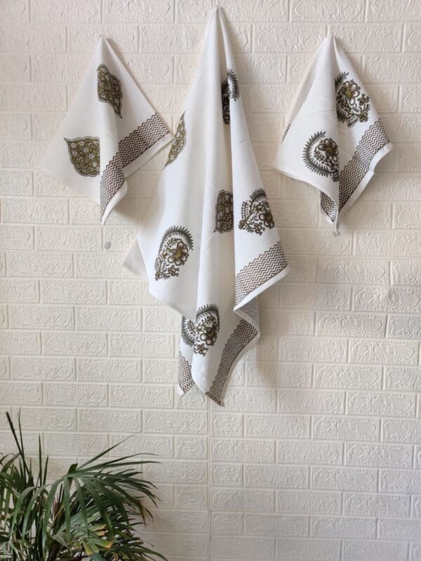 A trio of white towels, consisting of a single bath towel and two hand towels, gracefully displayed on a wall.