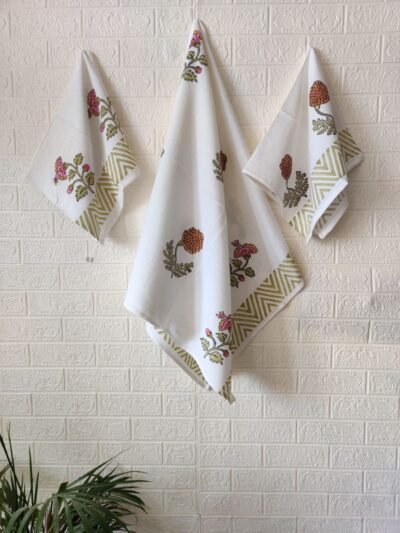 Three white towels, including a hand and bath towel, neatly hung on a wall.