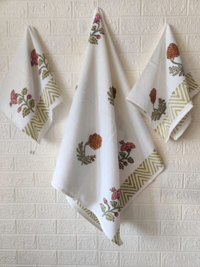 Three white towels, including a hand and bath towel, neatly hung on a wall.