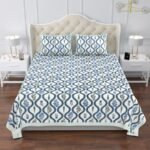 king size bed with a blue and white bedspread featuring a jaal print and flowers.