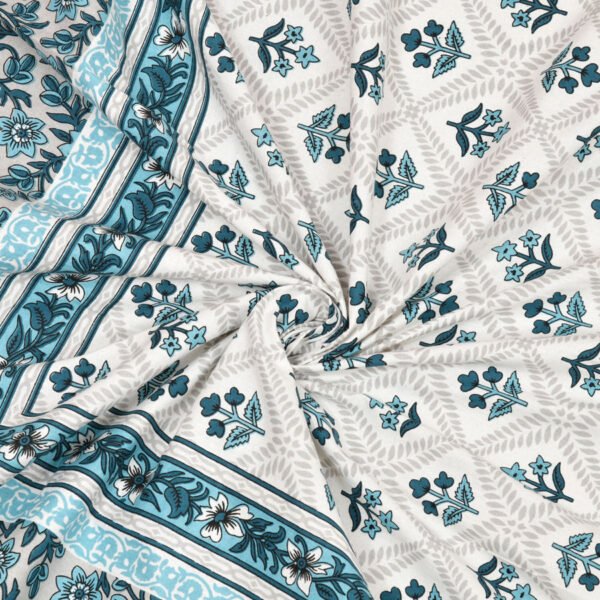 Close-up view of a blue and white floral print fabric with a curled up appearance by a blue border.