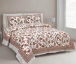 A brown and cream paisley print double dohar made from mulmul cotton, displayed on a bed in a bedroom setting