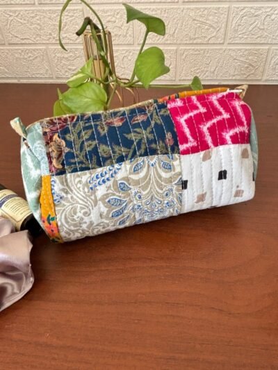 Handcrafted patchwork toiletry bag made with colorful fabric scraps, featuring a zipper closure and wrist strap.